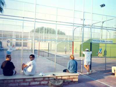 Ranieri ci fa vedere alcune foto di quegli anni che mostrano i due campi all�aperto posti uno accanto all�altro, racchiusi dalla tipica struttura di vetro e con la scritta �Federazione italiana gioco paddle� su un�insegna. La targa testimonia come prima questo sport si chiamasse �paddle� (in inglese �pagaia�): termine usato per indicare le racchette di legno che venivano utilizzate in principio per giocare